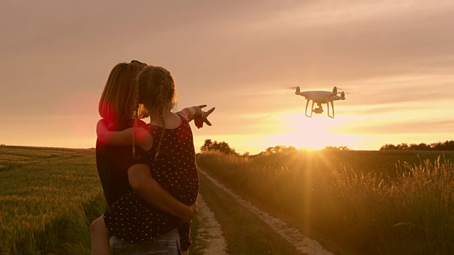 日落时分，母女俩向飞翔的无人机挥手视频下载