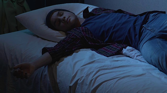 大学生参加完学生聚会后，穿着衣服睡在床上，晚上做梦视频素材