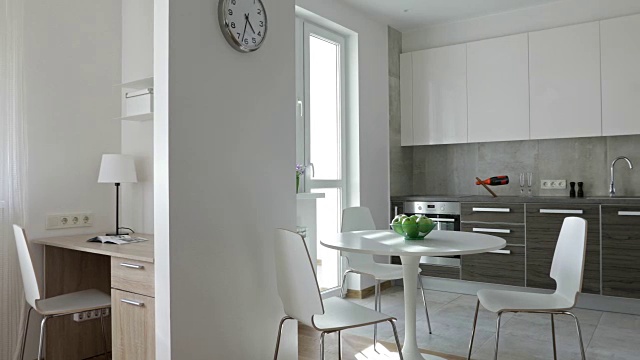 4 k编译视频。斯堪的纳维亚风格的现代公寓内部配备厨房和工作场所。移动全景与苹果和鲜花视频素材