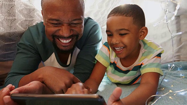父亲和儿子在卧室里使用数码平板电脑视频素材