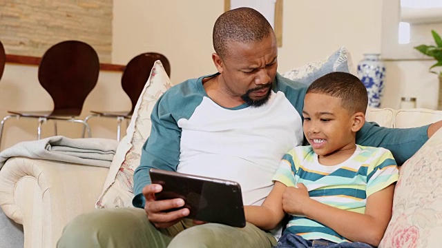父亲和儿子在客厅里使用数码平板电脑4k视频素材