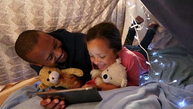 父亲和女儿在卧室里使用数码平板电脑视频素材