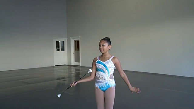 一个年轻女孩在舞蹈工作室里挥动指挥棒视频素材