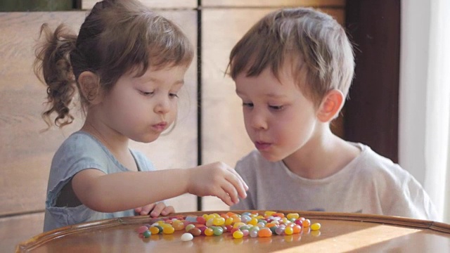 可爱的孩子们在吃五颜六色的糖果视频素材