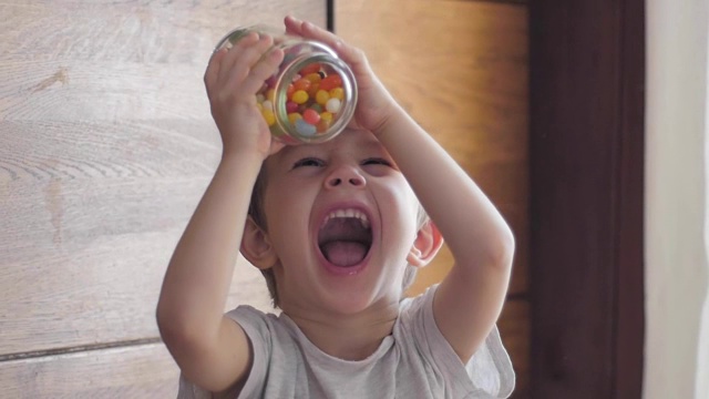 男孩在吃从罐子里掉下来的糖果视频素材