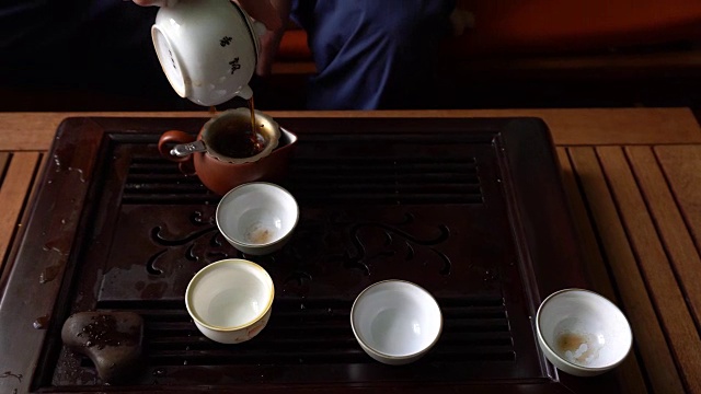 在中国传统茶道上，一名男子用茶壶倒普洱茶。一套饮茶设备视频下载