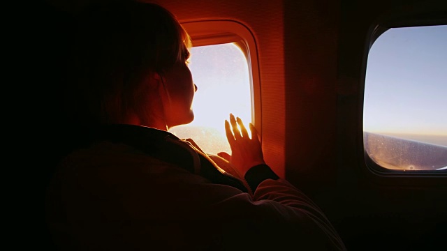 一名年轻女子从客机的窗口望着太阳。它能接触到阳光。概念-触摸梦想，完美的旅行和度假视频下载