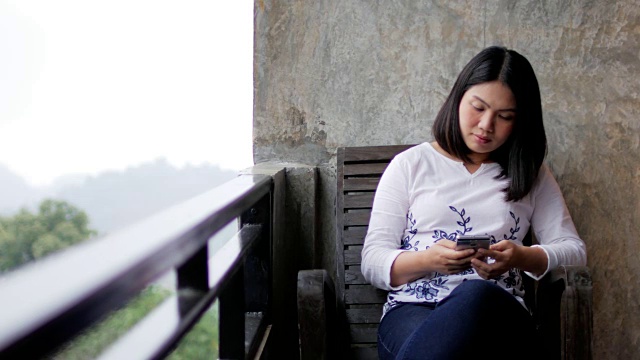 女人在阳台上使用智能手机在户外放松时间视频下载