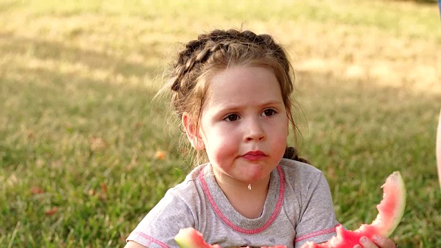 小女孩坐在草地上吃西瓜视频素材