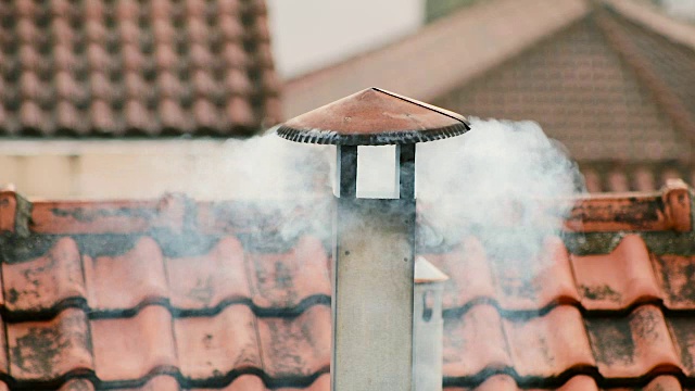 烟从房子的烟囱里冒出来。屋顶上的管子。烟囱。中国的房子。有烟囱的房子。屋顶上的烟视频素材