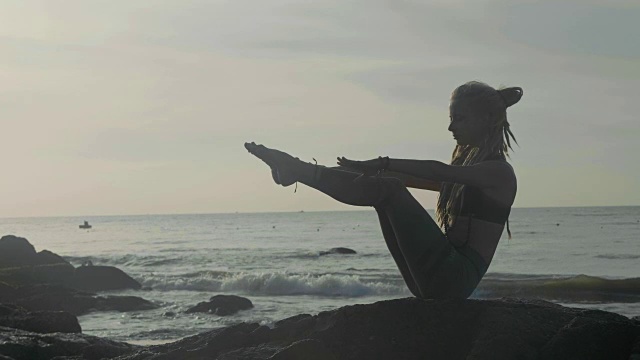 日落时练习剪影瑜伽。一个年轻女人在海滩上做瑜伽运动视频素材