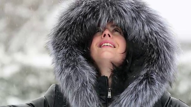 年轻漂亮的女子在暴风雪中穿着皮大衣视频素材