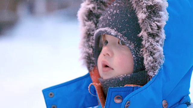 可爱的小男孩在暴风雪中穿着皮大衣视频素材