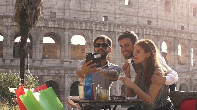 快乐的年轻夫妇游客自拍与漂亮的意大利优雅的服务员坐在酒吧餐厅在罗马斗牛场在日落开玩笑和大笑的乐趣视频素材
