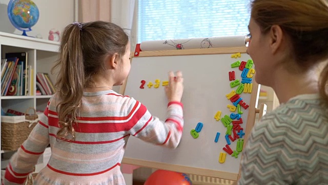 年轻的母亲在家给可爱的小女儿讲解算术视频素材