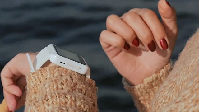 女人在日落时使用可穿戴智能手表。视频素材