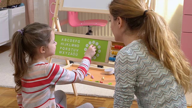 儿童早期发展。小女孩在家里用钟表玩具学习时间视频素材