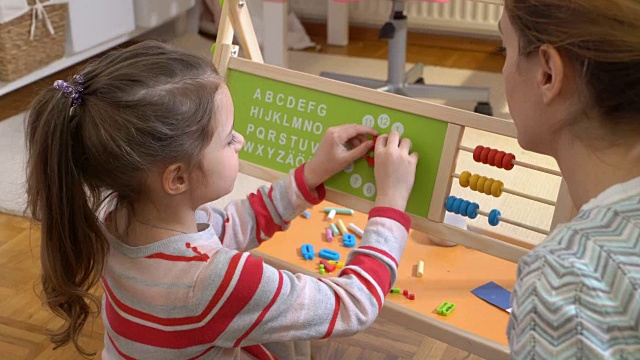 儿童早期发展。小女孩在家里用钟表玩具学习时间视频素材
