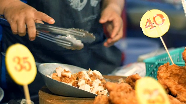 一位妇女用一种特制的刮刀拿起面包里的碎鸡块做食物。夜市，芭堤雅，宗田。泰国菜。市场上有亚洲异国菜肴视频素材