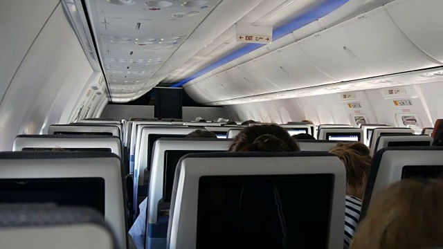 乘客坐在舒适的飞机座椅上，椅子上的屏幕上显示着地图视频素材
