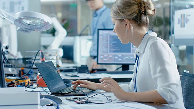女计算机科学家将电路板连接到她的笔记本电脑并开始编程。她在先进技术实验室工作。视频素材