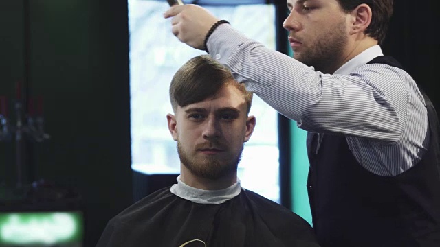 一个英俊的年轻人正在理发店理发视频素材