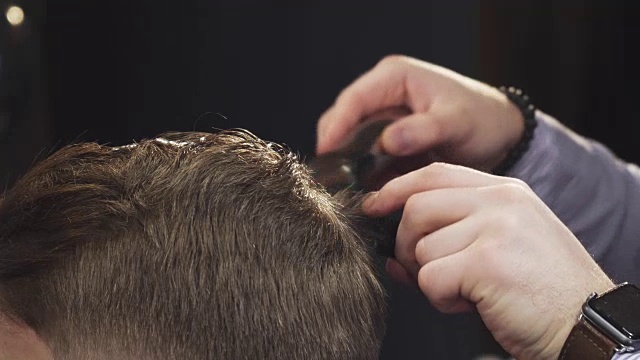 裁剪近距离的理发师剪他的客户的头发与一个修剪器视频素材