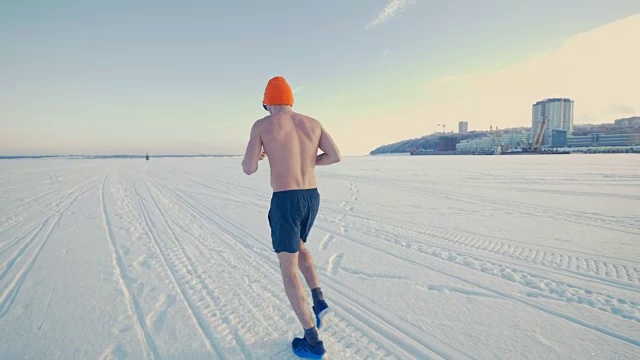 一个穿着跑步服的人在雪地上慢跑。视频素材