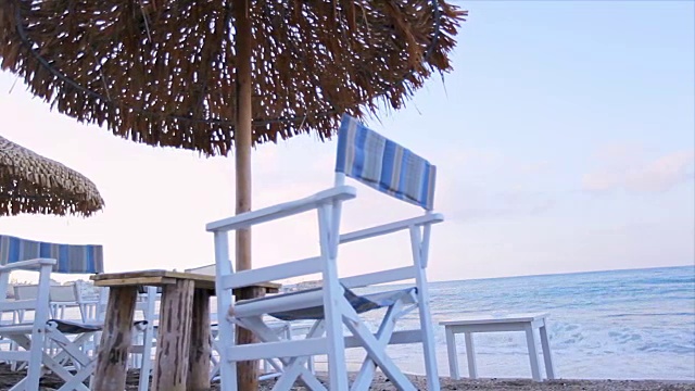 在沙滩上，撑着伞，坐在帆布躺椅上休息视频素材