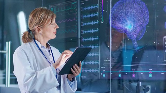 女性科学家使用平板电脑在现代大脑研究实验室和监测脑电图阅读和大脑模型功能。视频素材