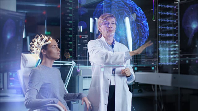 戴着脑电波扫描头戴耳机的女人坐在椅子上，科学家在扫描增强现实屏幕，显示大脑模型和脑电图数据。在现代大脑研究实验室。视频素材