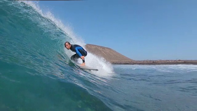 慢动作:年轻的冲浪者骑在管道波作为摄像机浸入清澈的海水。视频素材