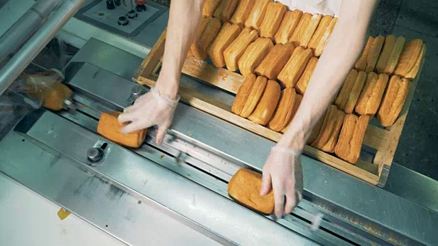 俯视图工人的手装载烘焙糕点包装。视频素材