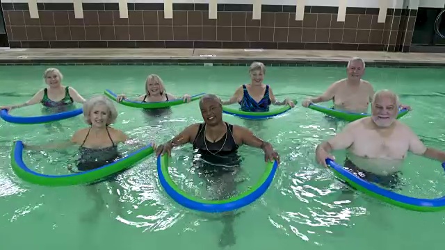 成熟的成年人在游泳池里用池面锻炼，看着镜头微笑。视频素材