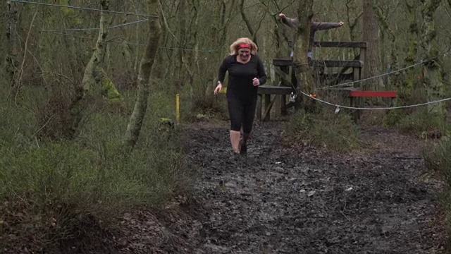 女子比赛泥跑通过林地-慢动作视频素材