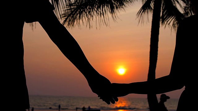 日落时分，在海滩上牵手的情侣视频素材