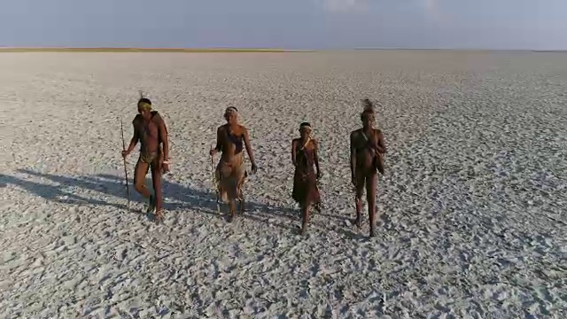 四名圣布须曼人在博茨瓦纳Makgadikgadi Pans的广阔地区行走的特写镜头和高空镜头视频素材