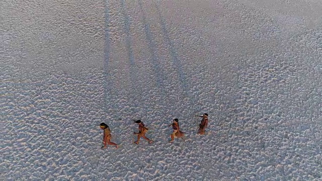 从空中俯瞰，四名圣布须曼人排成纵队，穿越广阔的博茨瓦纳Makgadikgadi pan视频素材