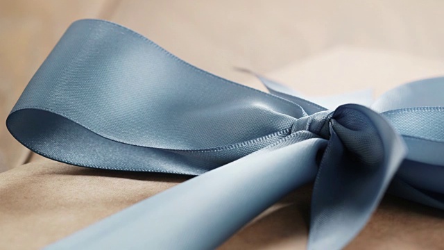 手工制作的棕色纸盒与蓝色丝带蝴蝶结在木桌上视频下载