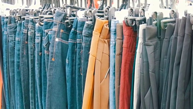 裤子挂在衣架上，女人看衣服就挑。跳蚤市场，在市场上出售的衣服视频素材