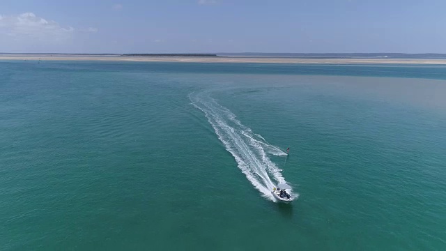 鸟瞰图，一个漂亮的年轻女孩拉着一艘快艇在一个美丽的河口冲浪视频素材