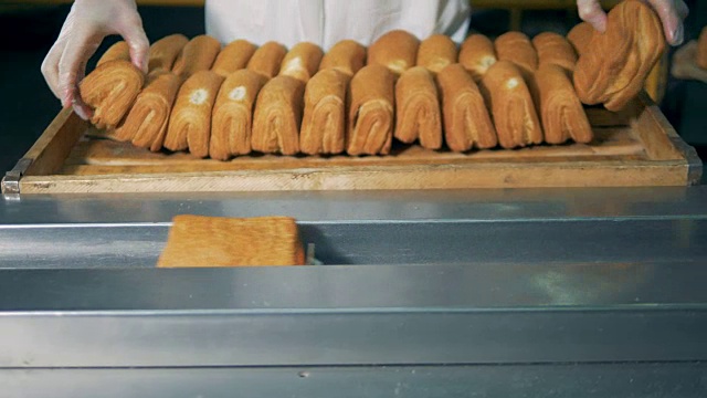 面包师正在往传送带上放松脆饼，正面。视频素材