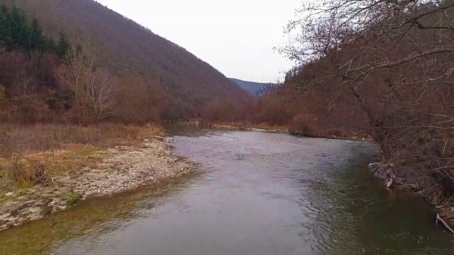 冬日里，一架无人机在山谷的河流上空拍摄视频素材