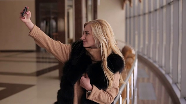 穿裘皮大衣的女孩在酒店大堂自拍视频素材