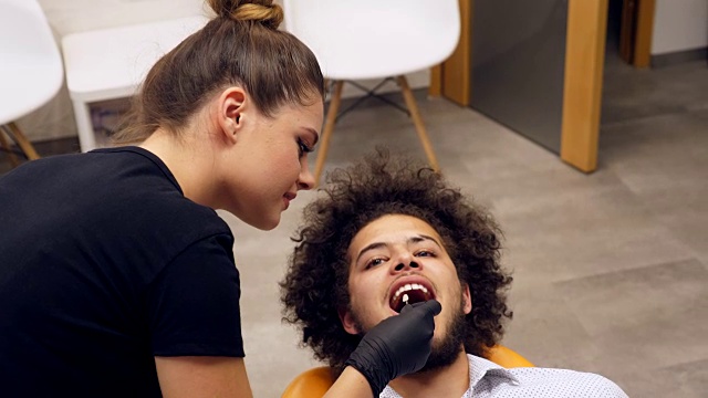 一名牙医助理检查一名年轻人牙齿颜色阴影的录像视频素材