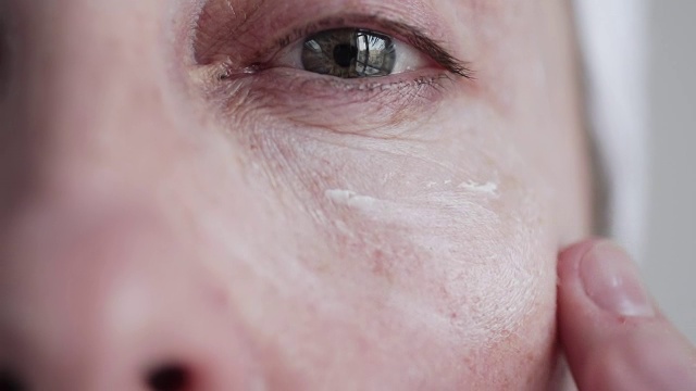 白人中年妇女在脸上涂霜。视频购买