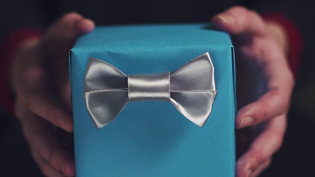 一名少女展示了一个带银色丝带和蝴蝶结的蓝色盒子视频下载