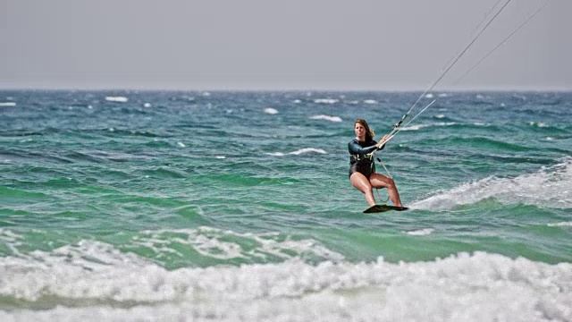SLO MO女人风筝滑板在汹涌的大海上视频素材