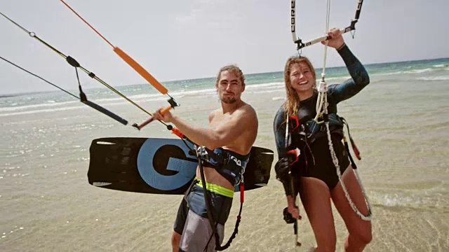 一个男性和女性风筝滑板者的肖像在海滩上放他们的风筝和微笑视频素材