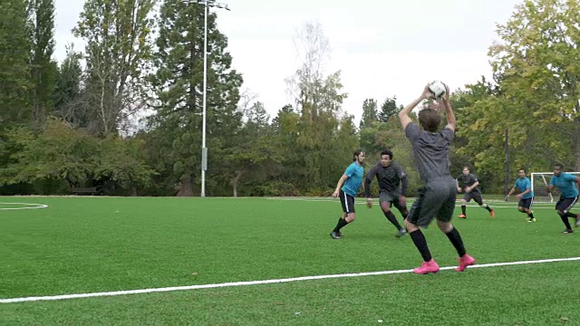 男子足球运动员投掷足球，运动员跑步。视频下载